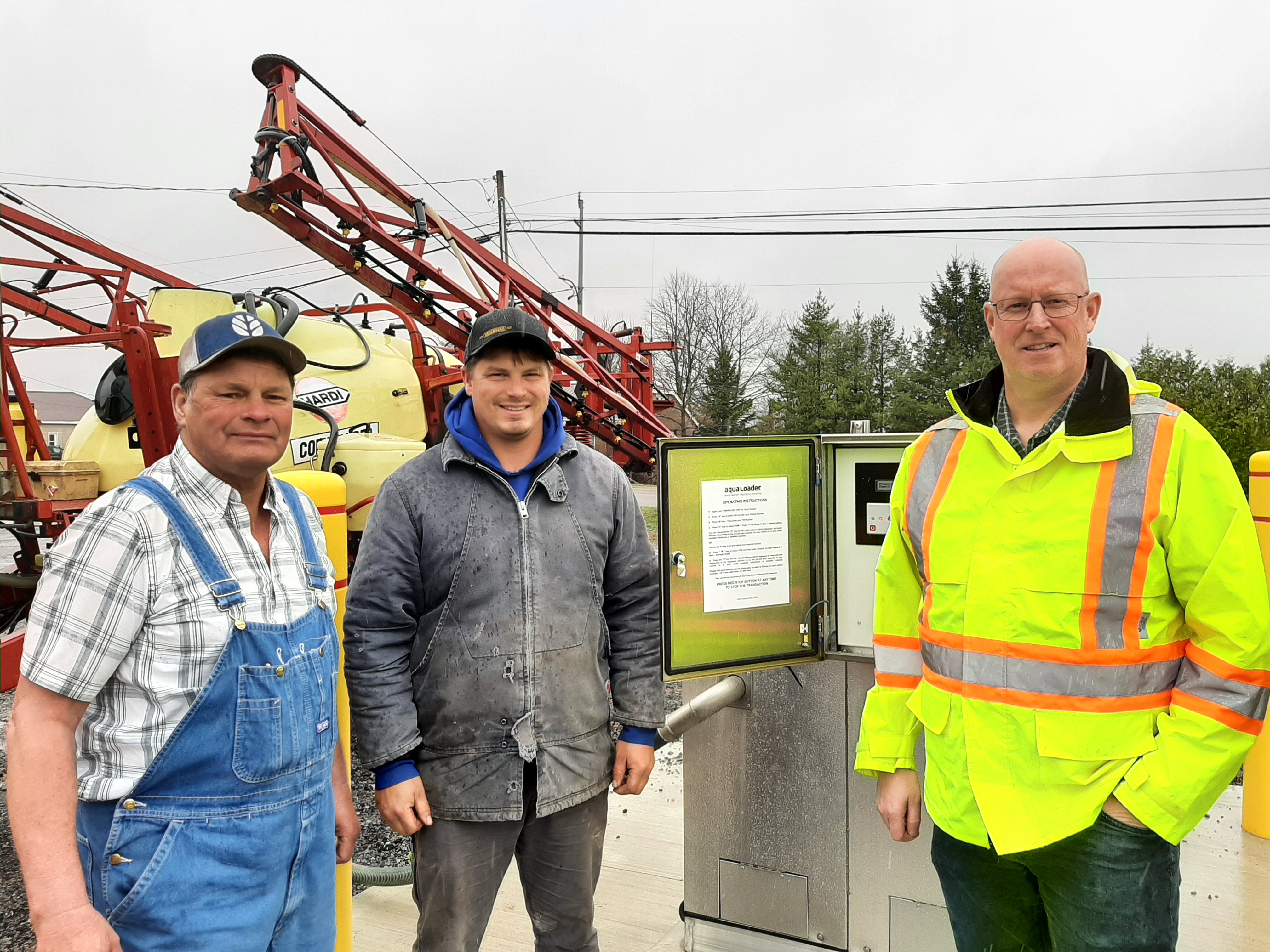 two local farmers and Township employee in front of new bulk water station