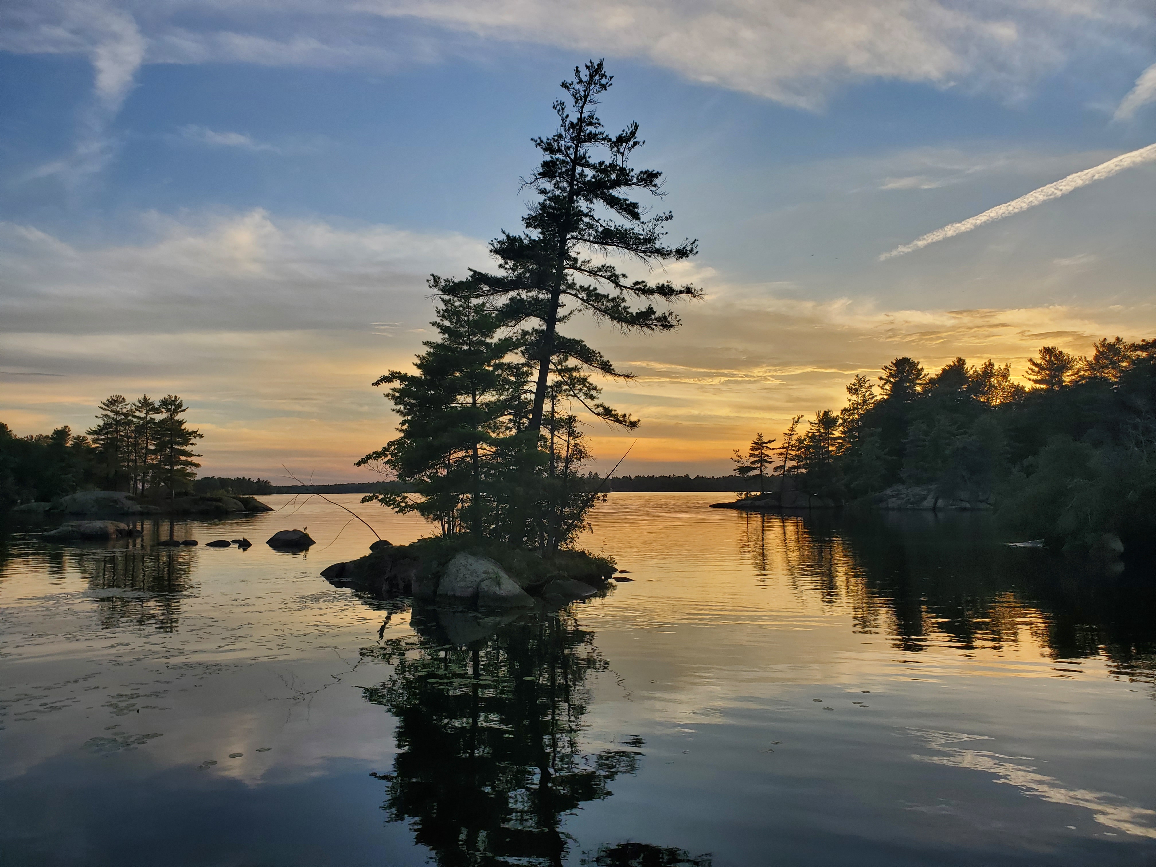 Sunset on very calm lake over looking pine trees