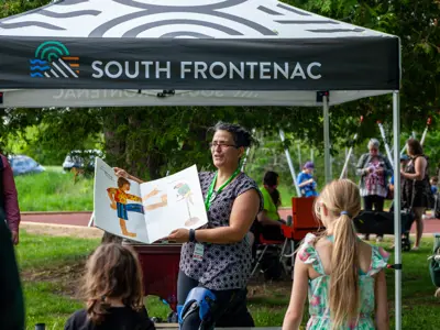 Woman at South Frontenac tent showing kids a book