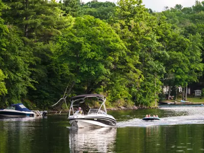 A boat cruising down the lake with a water tube behind it