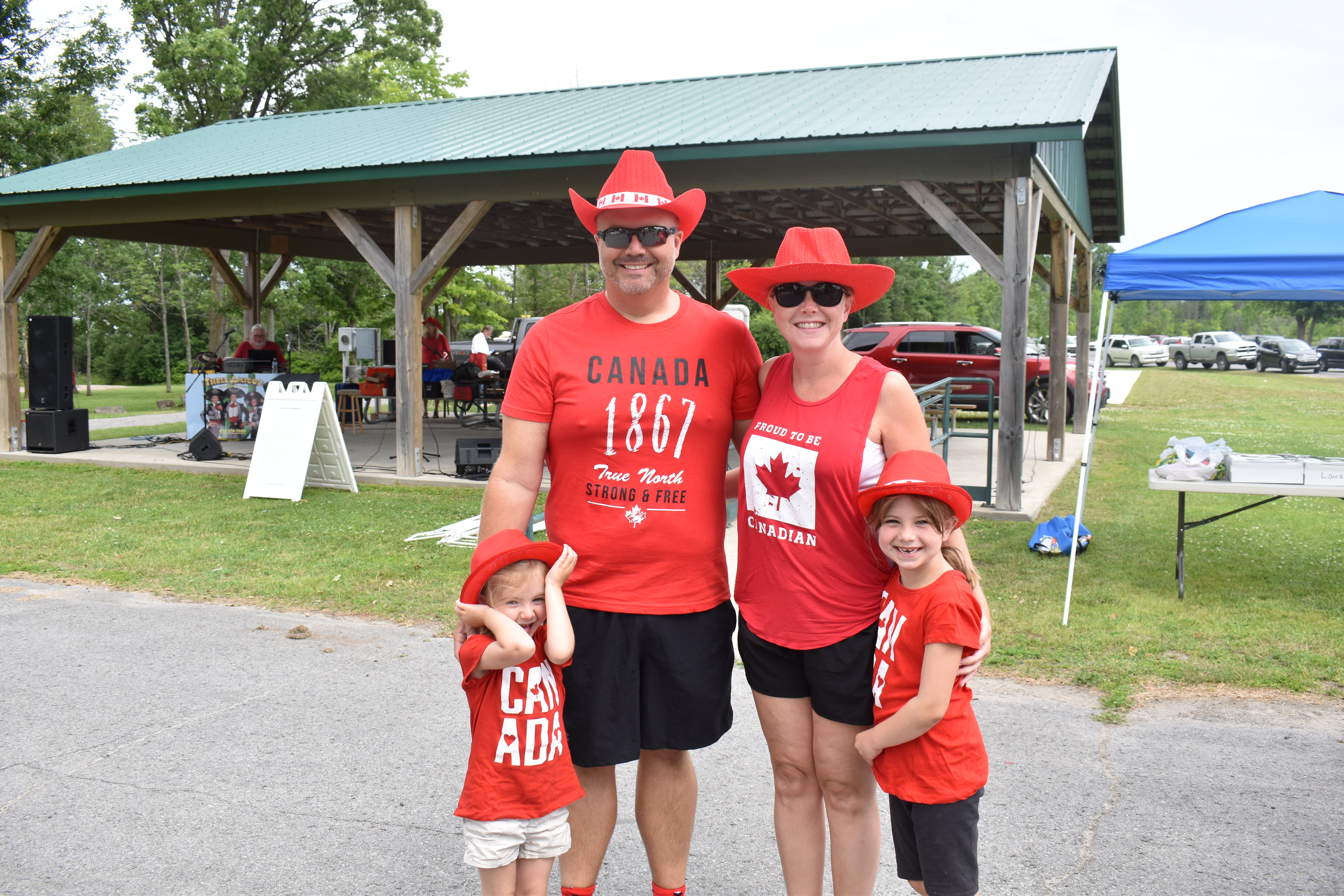 A family of four dressed in red and white for Canada Day poses for the camera 